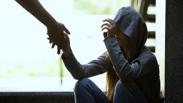 Person reicht einem einsamen depressiven Teenager die helfende Hand