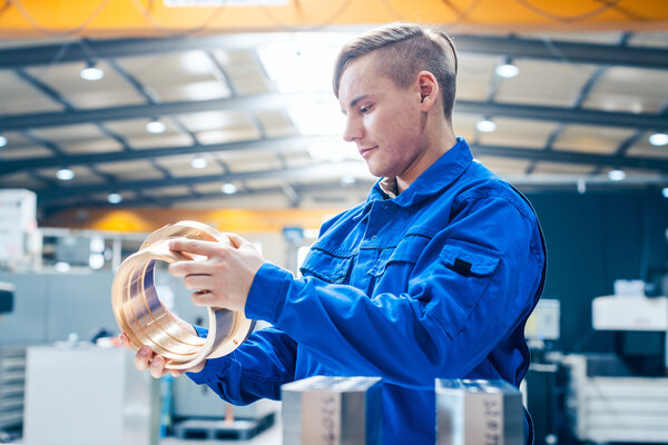 Metallarbeiter arbeitet an Metall Werkst&uuml;ck in einer Fertigungshalle.