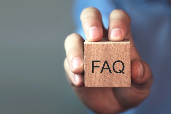 Hand h�lt einen Holzw�rfel, auf dem FAQ steht.